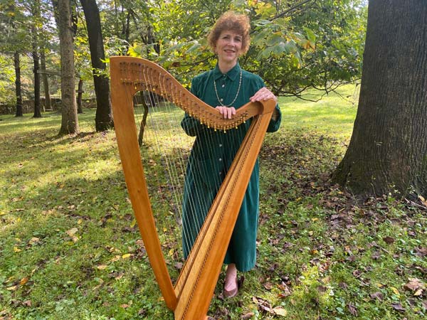 Anne standing behind her harp.